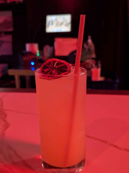Red-lit cocktail with citrus garnish